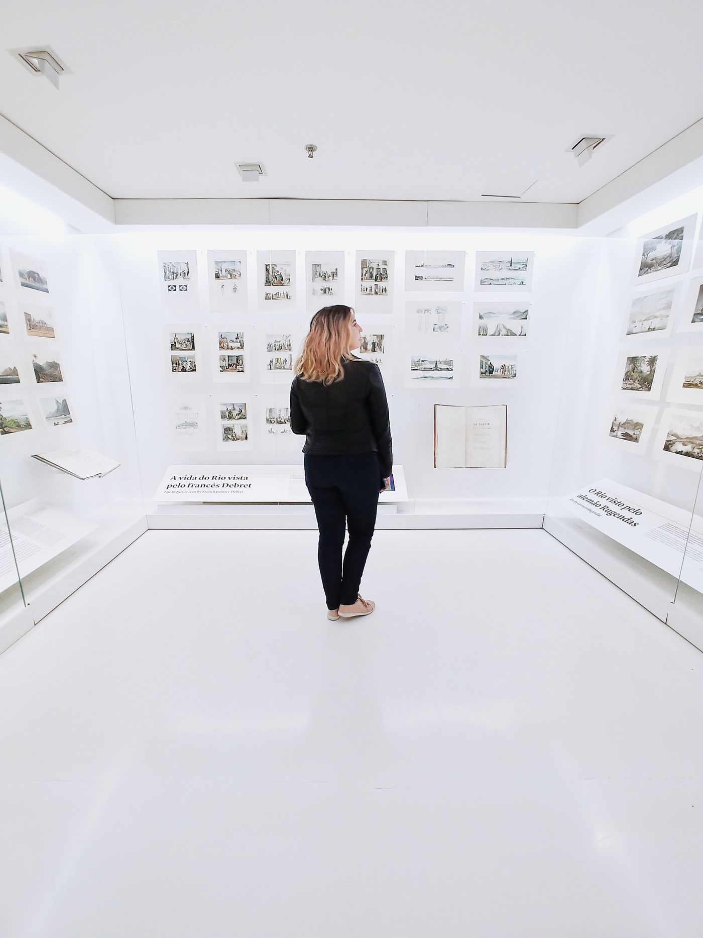 A visitor looking at works on paper displayed in a small gallery room